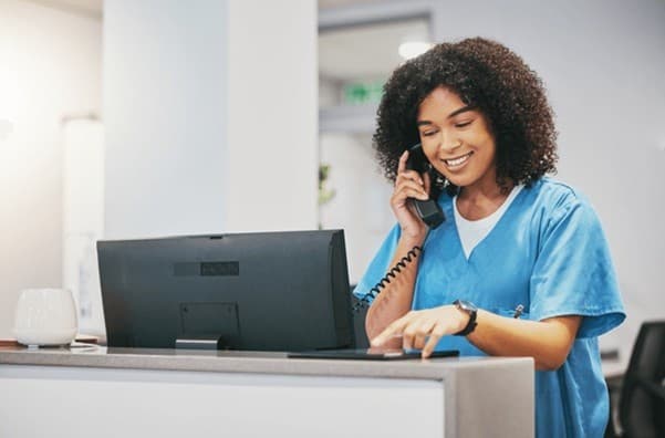 A nurse at a clinic reception desk, ready to help patients